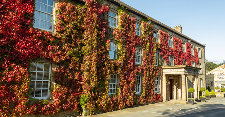External view of the Morritt Hotel's entrance covered in bright red ivy, Barnard Castle